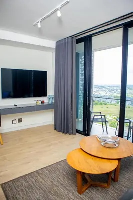 a living room with a table and a large window at Ellipse Waterfall Premium Apartments - Cream in Johannesburg
