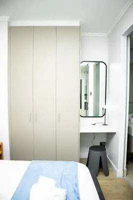 a white bedroom with a bed and a mirror at Ellipse Waterfall Premium Apartments - Cream in Johannesburg