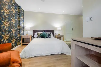 a bedroom with a large white bed with a floral wallpaper at Manor On Main in Midrand