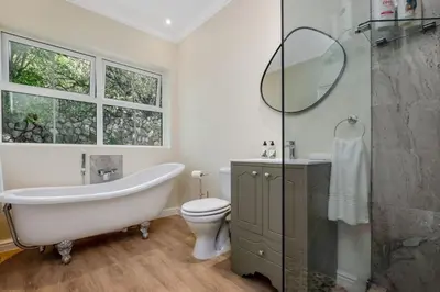 a bathroom with a tub and a toilet and a mirror at Manor On Main in Midrand