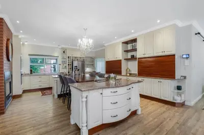 a kitchen with white cabinets and a large island at Manor On Main in Midrand