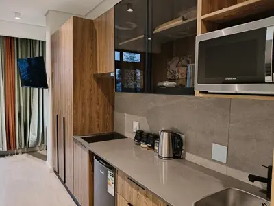 a kitchen with a counter with a sink and a microwave at Comfort at 35 Menlyn Maine Residences in Pretoria