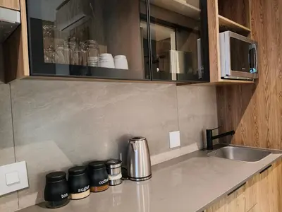 a kitchen with a counter top with a sink and coffeeutes at Comfort at 35 Menlyn Maine Residences in Pretoria