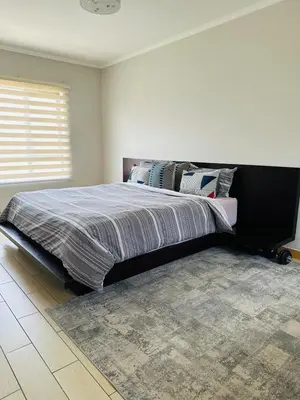 a bedroom with a large bed with a rug at Casa Maison - Stylish 3 Bedroom in Summerset, Midrand in Midrand