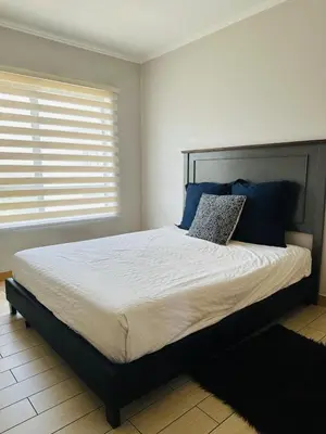 a bedroom with a large bed with blue pillows at Casa Maison - Stylish 3 Bedroom in Summerset, Midrand in Midrand