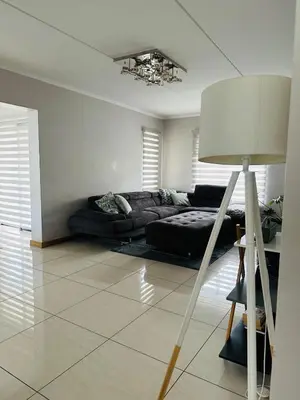 a living room with a couch and a lamp at Casa Maison - Stylish 3 Bedroom in Summerset, Midrand in Midrand