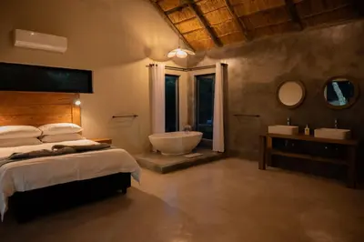 a bedroom with a bed and a tub and a sink at Timlia Marloth Park in Marloth Park