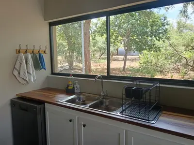 a kitchen with a sink and a large window at Timlia Marloth Park in Marloth Park