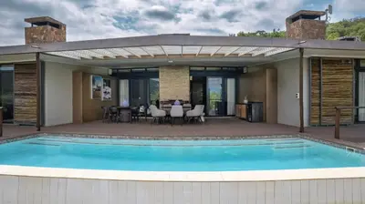 a swimming pool with a patio and a house at Babirwa in Rooiberg