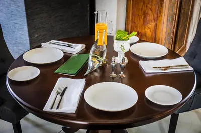a wooden table with white plates and a wine glass at Babirwa in Rooiberg