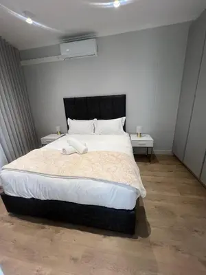a bedroom with a large bed with two tables at Havana at Ellipse Waterfall in Midrand