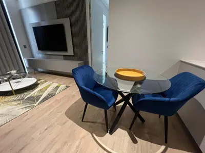 a glass table and two blue chairs in a room at Havana at Ellipse Waterfall in Midrand