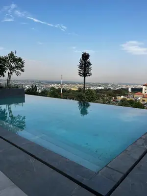 a swimming pool with a view of a city at Ellipse Waterfall 2BR with Pool, Restaurant & Gym in Midrand