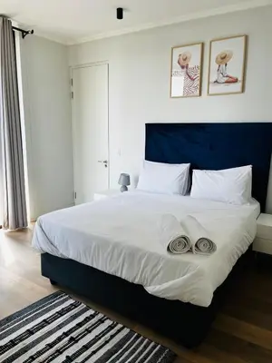 a bedroom with a large bed with two towels on it at Ellipse Waterfall 2BR with Pool, Restaurant & Gym in Midrand