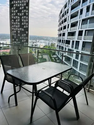a table and chairs on the balcony of a building at Ellipse Waterfall 2BR with Pool, Restaurant & Gym in Midrand