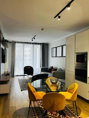 a living room with a glass table and yellow chairs at Ellipse Waterfall 2BR with Pool, Restaurant & Gym in Midrand
