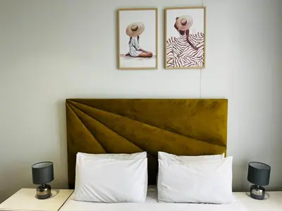 a bed with two pillows and two pictures on the wall at Ellipse Waterfall 2BR with Pool, Restaurant & Gym in Midrand