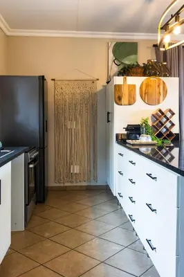 a kitchen with white cabinets and a black refrigerator at Shekinah Cabin in Hartbeespoort