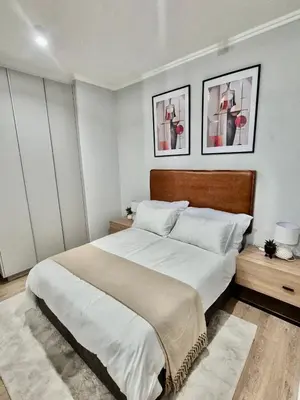 a bedroom with a large bed with two pictures on the wall at One Palm at Ellipse Waterfall in Midrand