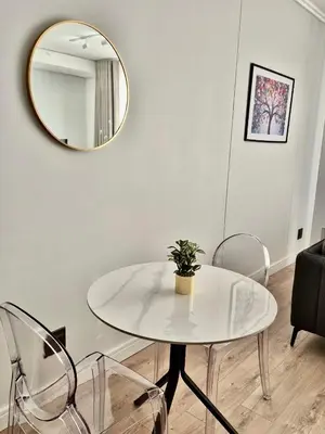 a table and chairs in a living room with a mirror at One Palm at Ellipse Waterfall in Midrand