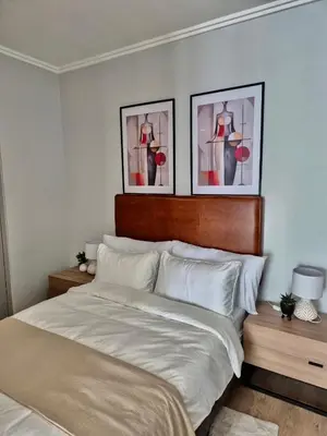a bedroom with a bed with two pictures on the wall at One Palm at Ellipse Waterfall in Midrand