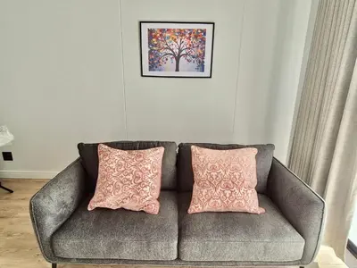 a couch with two pink pillows in a living room at One Palm at Ellipse Waterfall in Midrand