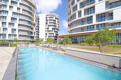a swimming pool in front of two tall buildings at One Palm at Ellipse Waterfall in Midrand