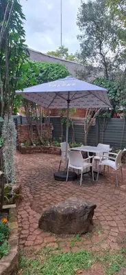 a patio with a table and chairs and an umbrella at Olive Studio in Pretoria