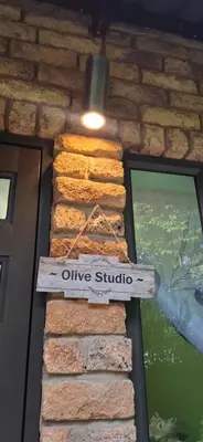 a sign that says olive studio on a brick wall at Olive Studio in Pretoria