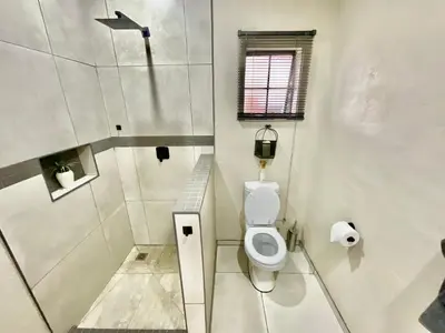 a white bathroom with a toilet and a window at ColtsRest in White River
