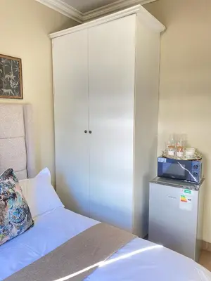 a bedroom with a white cabinet and a bed at Asanda Retreat in Kempton Park