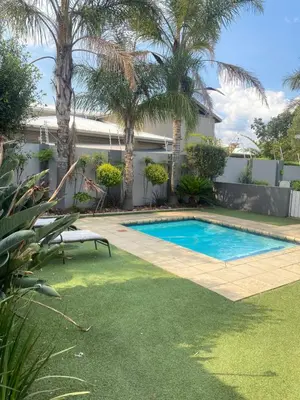a swimming pool in a yard with palm trees at Asanda Retreat in Kempton Park
