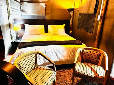 a bedroom with a bed and two chairs at Thaba View Luxury Tent in Hartbeespoort