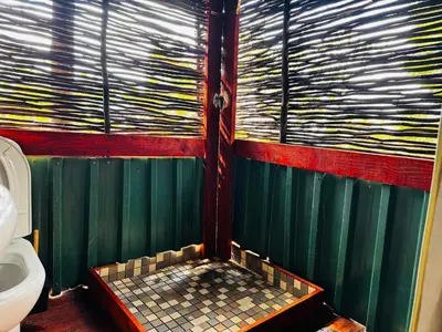 a bathroom with a tiled shower with a toilet at Thaba View Luxury Tent in Hartbeespoort