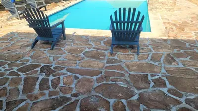 two chairs sitting next to a swimming pool at Thombo Bush Lodge And Camp