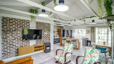 a living room with a tv and a brick wall at Cottage Daisy in Doornrandjies
