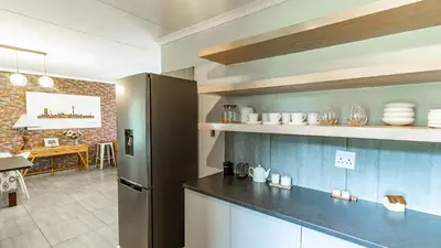 a kitchen with a stainless steel refrigerator and a dining room at Cottage Protea in Doornrandjies