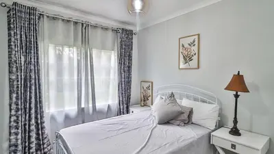 a white bedroom with a bed and a window at Cottage Protea in Doornrandjies