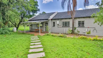 a white house with a pathway in front of a yard at Cottage Protea in Doornrandjies