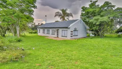 a small white house in a field of grass at Cottage Protea in Doornrandjies