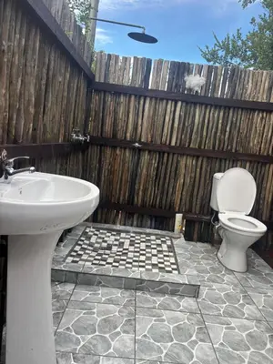 a bathroom with a sink and a toilet in front of a fence at Inn Africa Safari Camp in Welverdiend