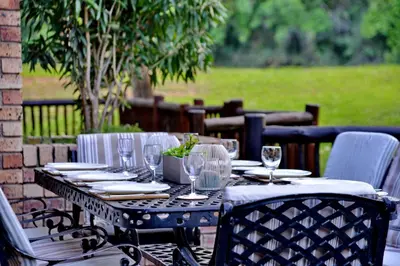 an outdoor table with glasses and plates on it at Cambalala - Luxury Units - in Kruger Park Lodge - Serviced Daily, Free Wi-Fi in Hazyview