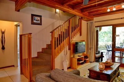 a living room with a staircase and a tv at Cambalala - Luxury Units - in Kruger Park Lodge - Serviced Daily, Free Wi-Fi in Hazyview