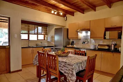 a kitchen with a table with chairs and a tableasteryasteryasteryasteryasteryastery at Cambalala - Luxury Units - in Kruger Park Lodge - Serviced Daily, Free Wi-Fi in Hazyview