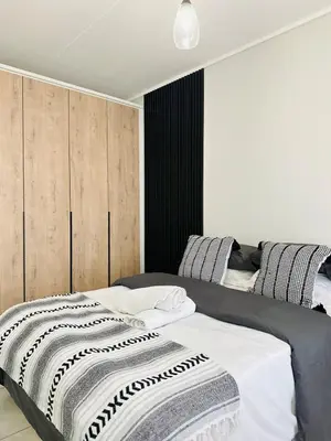 a bedroom with a bed with a black and white blanket at Lagoon Luxury Stay 2 bed apartment at The Blyde in Pretoria
