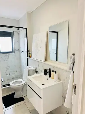 a white bathroom with a toilet and a sink at Lagoon Luxury Stay 2 bed apartment at The Blyde in Pretoria