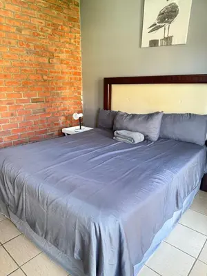 a large bed in a room with a brick wall at 2 bed room apartment in the heart of midrand in Erand