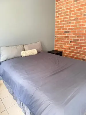 a large bed in a room with a brick wall at 2 bed room apartment in the heart of midrand in Erand