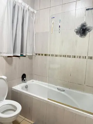 a bathroom with a white tub and a toilet and a shower at 2 bed room apartment in the heart of midrand in Erand