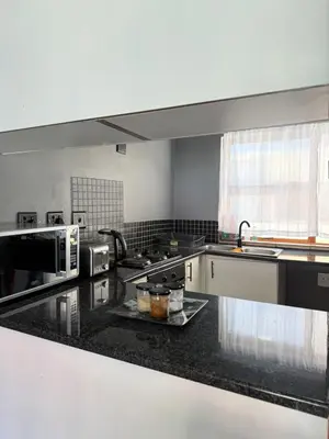 a large kitchen with black counter tops and appliances at 2 bed room apartment in the heart of midrand in Erand